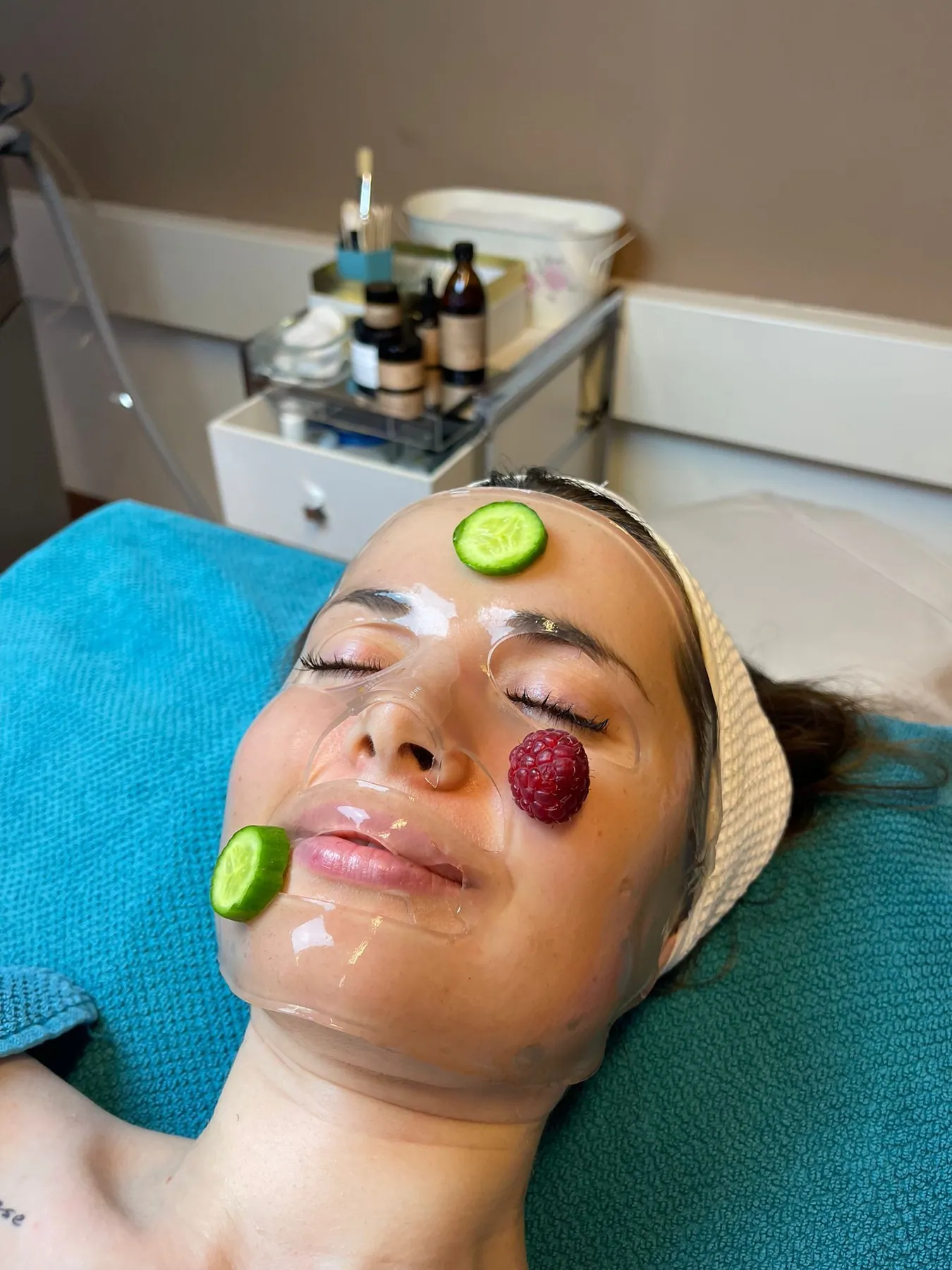 Kundin mit Gesichtsmaske, Gurken- und Fruchtscheiben auf der Haut